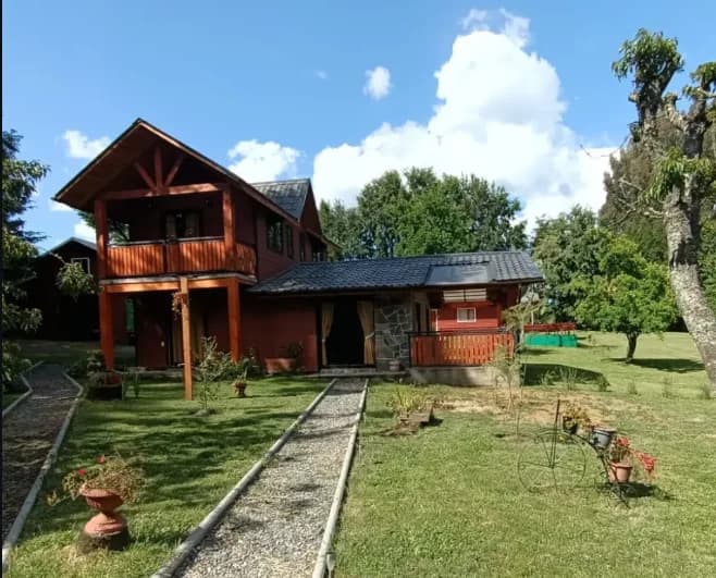 Cabaña de madera con jardín y sendero de piedra en el sur de Chile